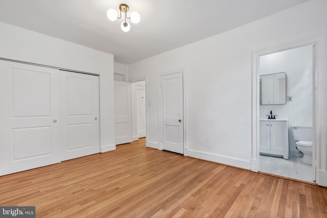 unfurnished bedroom with ensuite bath, sink, a closet, and light wood-type flooring