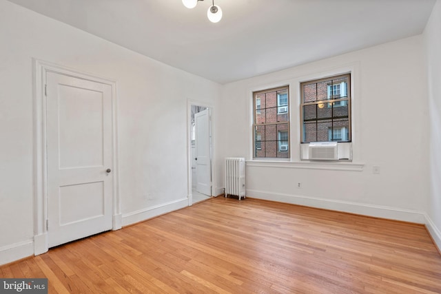 spare room featuring radiator and light wood-type flooring