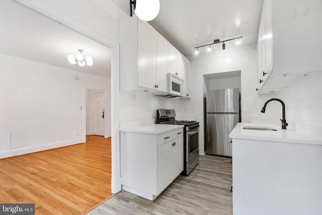 kitchen with light wood-type flooring, appliances with stainless steel finishes, sink, and white cabinets