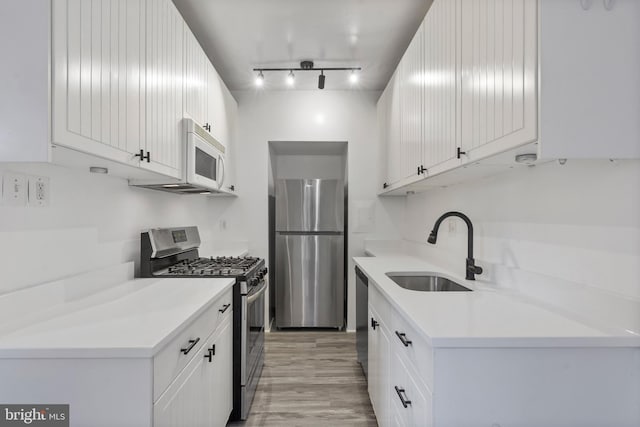 kitchen featuring white cabinetry, appliances with stainless steel finishes, sink, and light hardwood / wood-style floors