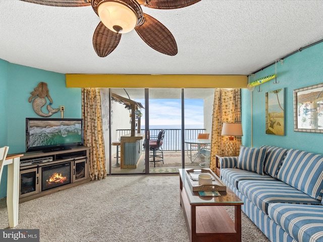 living room with ceiling fan, carpet floors, and a textured ceiling