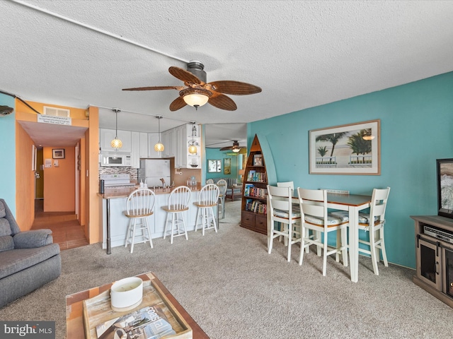 living room with light carpet, ceiling fan, and a textured ceiling