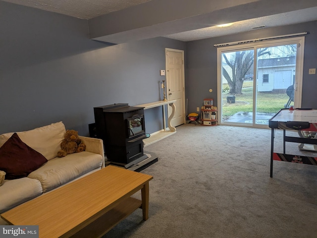 living room featuring carpet floors, a wood stove, and a textured ceiling