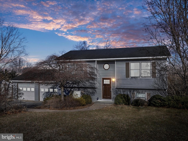 bi-level home featuring a garage and a lawn