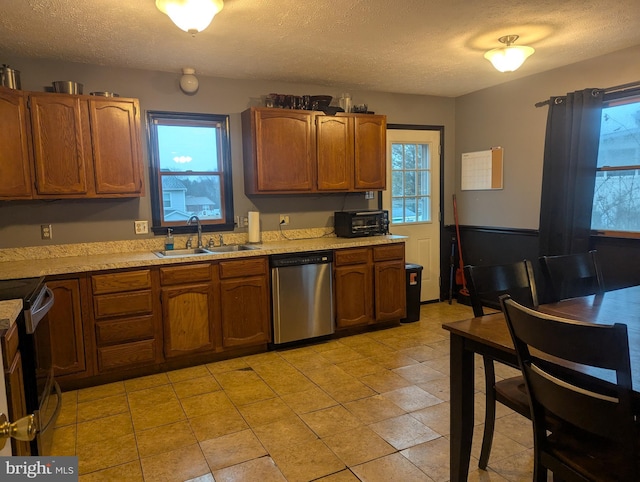 kitchen with appliances with stainless steel finishes, sink, a textured ceiling, and a wealth of natural light