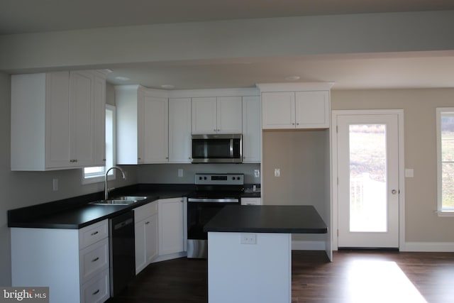 kitchen featuring sink, appliances with stainless steel finishes, dark hardwood / wood-style floors, a kitchen island, and white cabinets