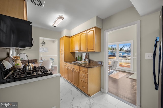 kitchen with hanging light fixtures, dark stone counters, and black appliances