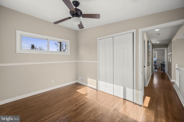 unfurnished bedroom with dark wood-type flooring, a closet, and ceiling fan