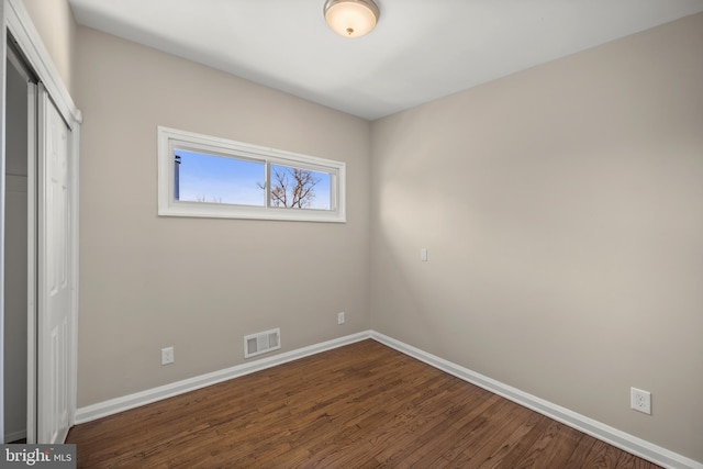 unfurnished bedroom with dark hardwood / wood-style flooring and a closet