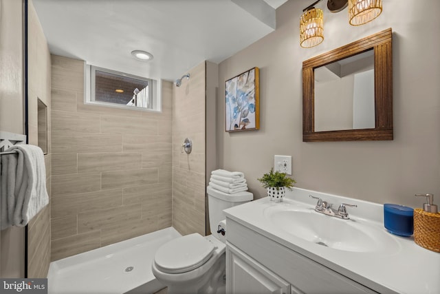 bathroom with vanity, toilet, and tiled shower