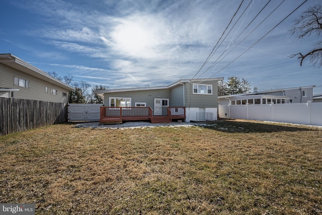 rear view of property featuring a wooden deck and a lawn