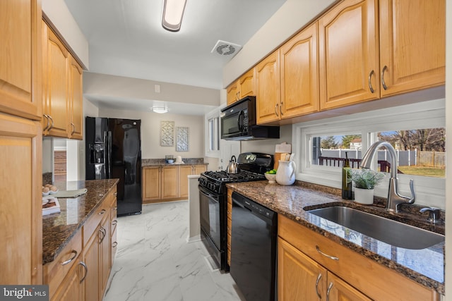 kitchen featuring dark stone counters, sink, and black appliances