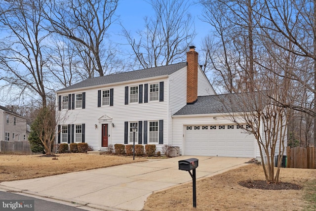 colonial inspired home featuring driveway, a shingled roof, a chimney, an attached garage, and fence