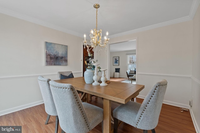 dining space featuring crown molding, baseboards, and wood finished floors