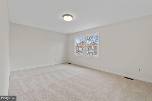 unfurnished room with carpet, visible vents, and baseboards