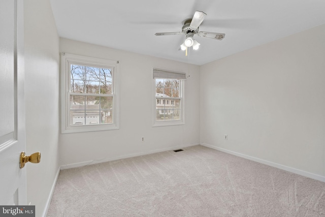 unfurnished room with carpet, visible vents, baseboards, and ceiling fan