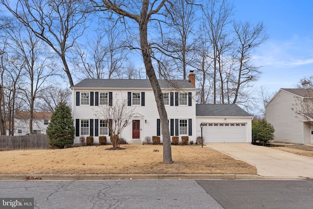 colonial inspired home with driveway, a chimney, a garage, and fence