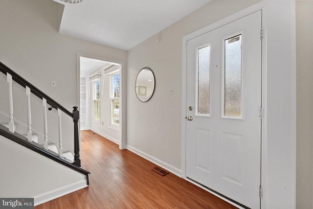 foyer with stairs, wood finished floors, visible vents, and baseboards