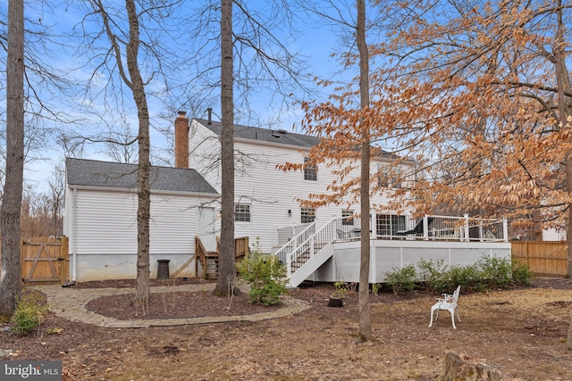 rear view of house featuring fence, stairs, roof with shingles, a wooden deck, and a chimney