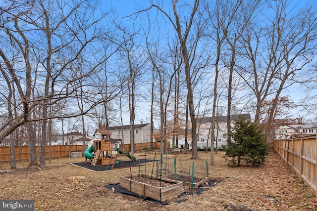 view of jungle gym featuring a fenced backyard and a vegetable garden