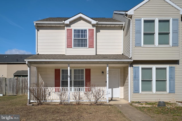 view of front of property with a porch, a shingled roof, and fence