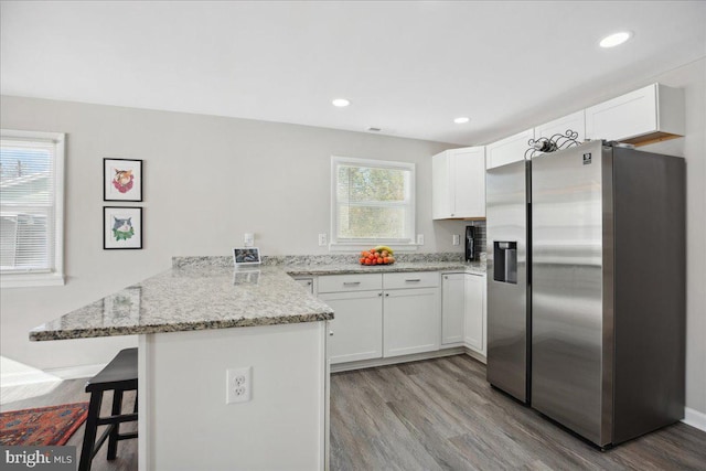 kitchen with stainless steel refrigerator with ice dispenser, kitchen peninsula, and white cabinets