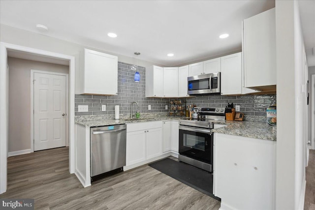 kitchen featuring sink, white cabinets, light stone counters, light hardwood / wood-style floors, and stainless steel appliances