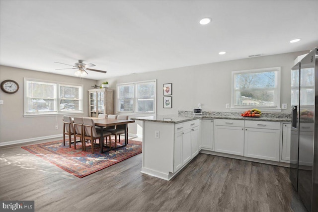 kitchen featuring white cabinetry, dark hardwood / wood-style flooring, light stone countertops, and kitchen peninsula