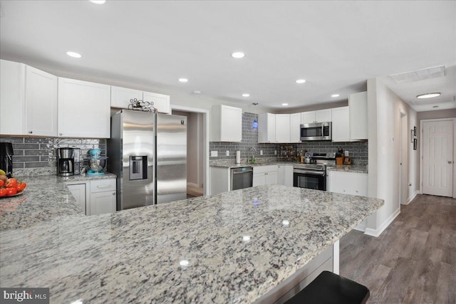 kitchen featuring white cabinetry, stainless steel appliances, kitchen peninsula, and a breakfast bar area