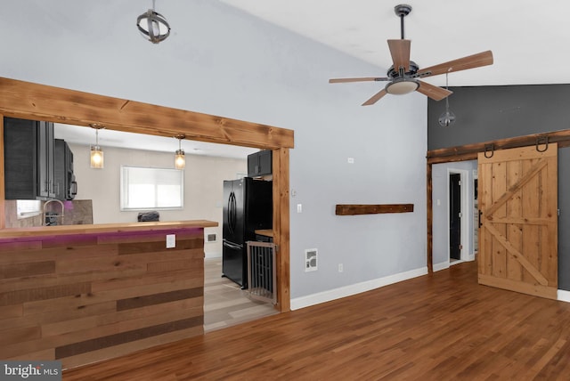 interior space featuring vaulted ceiling, wood-type flooring, sink, ceiling fan, and a barn door