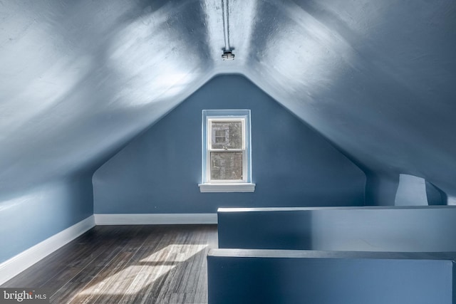 bonus room with dark wood-type flooring and vaulted ceiling