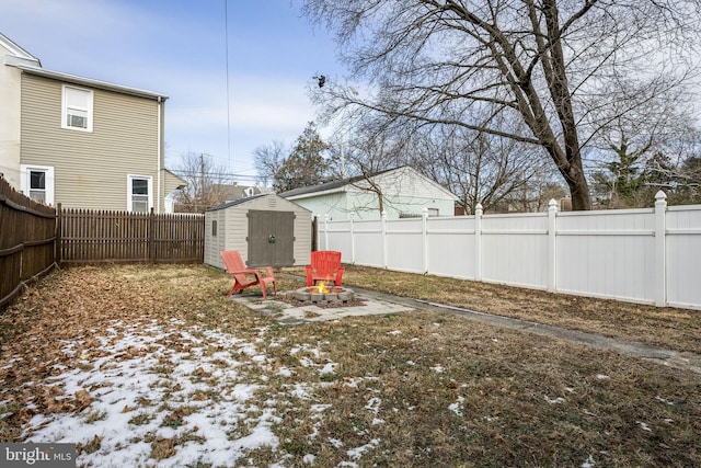 yard layered in snow with an outdoor fire pit and a storage unit