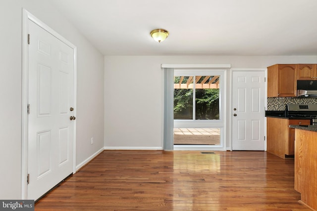 11501 Piney Lodge Rd, North Potomac, MD 20878 - kitchen featuring stainless steel gas range oven, dark countertops, wood finished floors, and backsplash
