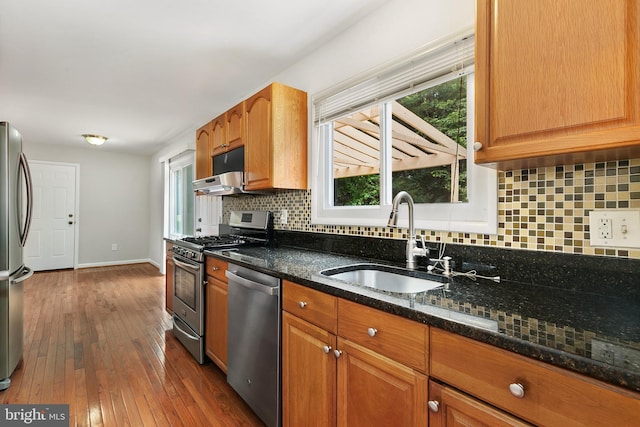 11501 Piney Lodge Rd, North Potomac, MD 20878 - kitchen featuring stainless steel appliances, a sink, dark stone counters, dark wood finished floors, and backsplash