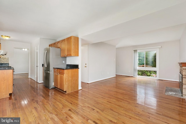 11501 Piney Lodge Rd, North Potomac, MD 20878 - kitchen with freestanding refrigerator, light wood-style flooring, dark countertops, baseboards, and extractor fan