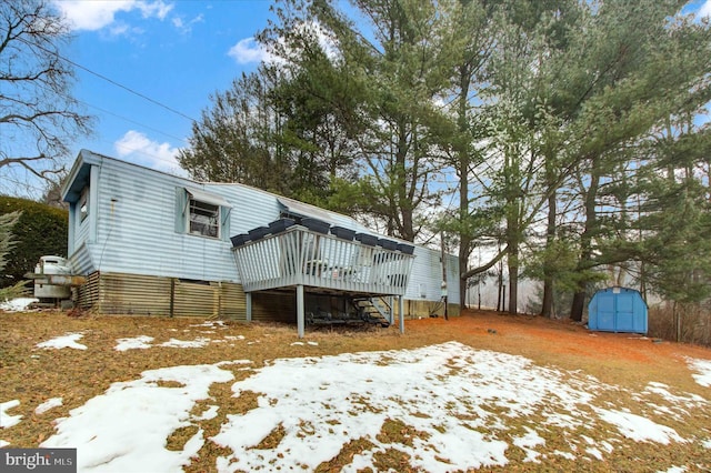 snow covered house with a deck and a shed