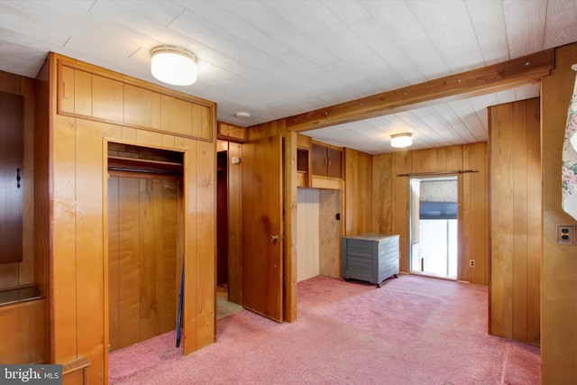 bedroom featuring elevator, wood walls, beamed ceiling, carpet, and a closet