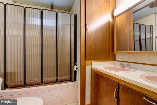 full bathroom with enclosed tub / shower combo, vanity, and toilet