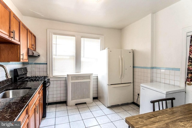 kitchen with sink, gas stove, tile walls, light tile patterned floors, and white fridge