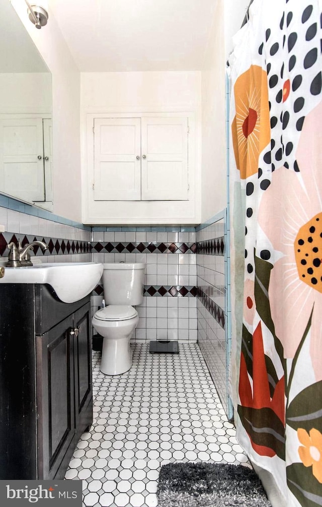 bathroom featuring vanity, toilet, a shower with shower curtain, and tile walls