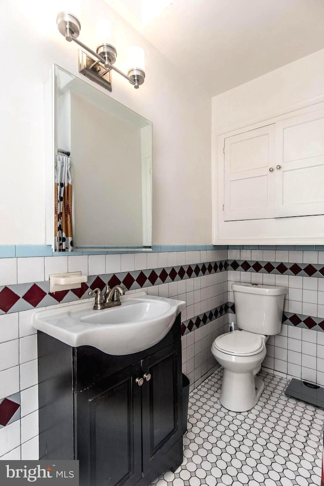 bathroom with vanity, tile walls, tile patterned floors, and toilet