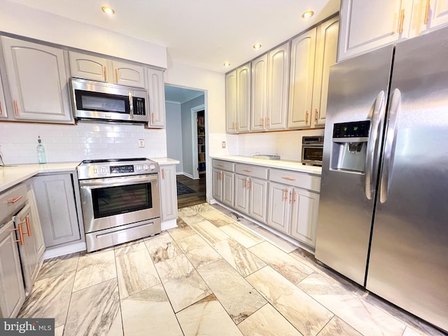 kitchen with appliances with stainless steel finishes, decorative backsplash, and gray cabinetry