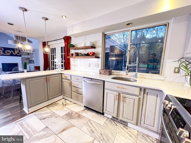 kitchen with sink, appliances with stainless steel finishes, hanging light fixtures, tasteful backsplash, and kitchen peninsula