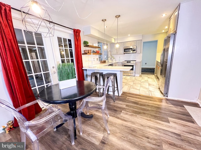 dining space with an inviting chandelier, sink, and light hardwood / wood-style flooring