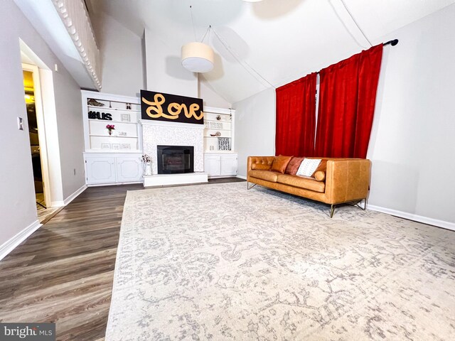 unfurnished living room featuring a tiled fireplace, dark wood-type flooring, built in features, and vaulted ceiling