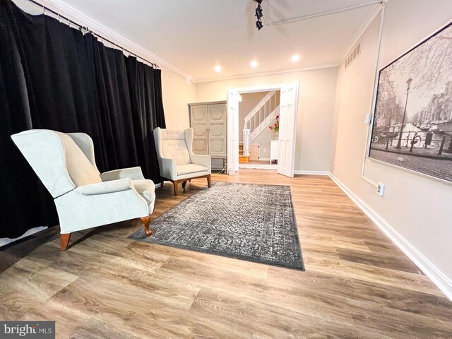 living area featuring crown molding and hardwood / wood-style flooring