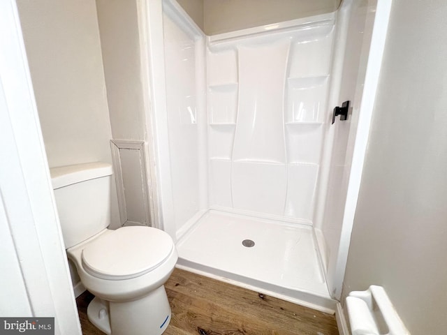 bathroom with hardwood / wood-style flooring, toilet, and walk in shower