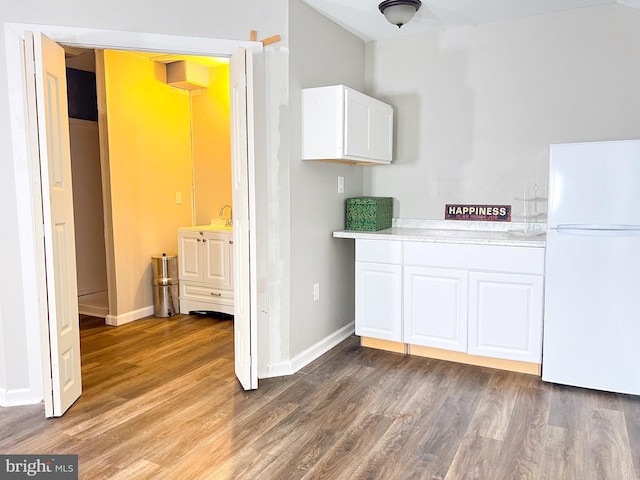 kitchen with sink, hardwood / wood-style flooring, white cabinets, and white refrigerator