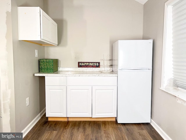 kitchen with white cabinetry, dark wood-type flooring, and white fridge