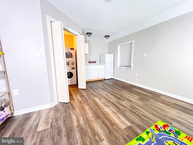 unfurnished living room featuring stacked washer / drying machine and hardwood / wood-style flooring